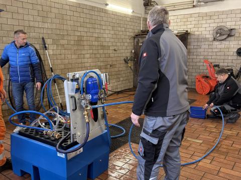 Drei Bauhofmitarbeiter bedienen das Desinfektionsgerät