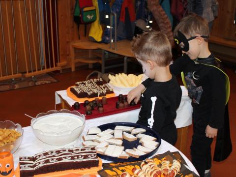 Zwei kostümierte Kinder bedienen sich am Halloween-Buffet.