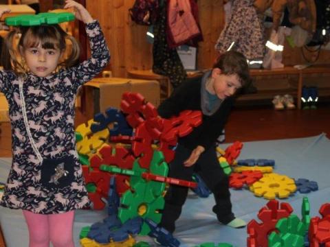 Kinder, die mit den neuen Steckblumen spielen. Ein Mädchen hält sich eine Steckblume wie einen Hut auf den Kopf.