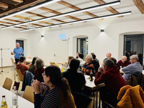 Bürger sitzen an Tischen und Bürgermeister Herbert Seitz moderiert die Veranstaltung.