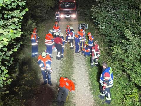 Die Verletztendarstellerpuppe liegt am Boden eines Waldwegs, die Retter um sich